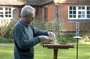 Images Dated 3rd November 2006: Man putting out crumbs for the birds on bird table