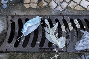 Mask and surgical gloves on top of urban sewer