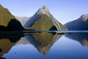 Milford Sound - landmark Mitre Peak and surrounding mountains reflected in the calm waters of Milford Sound in early