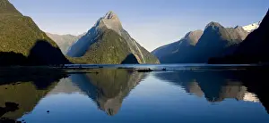 Milford Sound landmark Mitre Peak and surrounding mountains reflected in the calm waters of Milford Sound in early morning. Milford Sound is one of the, if not THE, most famous attraction in New Zealand