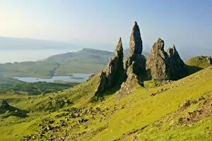 Mountain scenery - rolling green slopes and bizarre rock formation Old Man of Storr seen from above with view towards