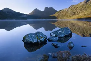 Mountain scenery - stunning Dove Lake in front of massive Cradle Mountain is one of Tasmania's most beautiful and famous natural features. In early morning there is still mist on the calm waters of Lake Dove