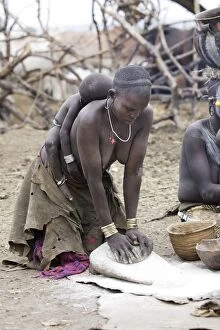 Images Dated 17th August 2005: Mursi people - woman preparing food with baby sleeping