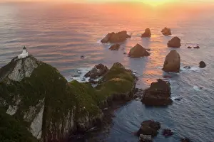 Sea Stacks Prints: Nugget Point sea stacks called nuggets and Nugget Point Lighthouse facing towards rising sun Catlins