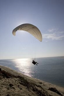 Paraglider silhouetted against evening sun over