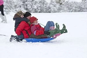 Parents and children sledging in deep snow on slopes