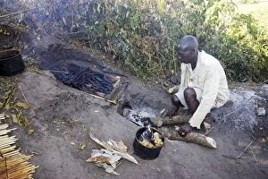 People - man cooking, with fish being cooked over fire