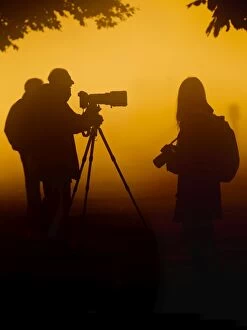 Photographers at sunrise in mist