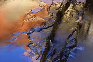 Reflections - a river cascades down Weano Gorge. The with sunlight ablaze red cliffs reflect in the water and give it an orange to bronze colour - Weano Gorge, Hamersley Range, Karijini National Park, Pilbara, Western Australia, Australia