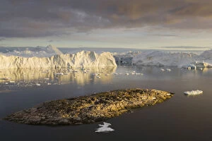 Iceberg Gallery: rocky island and large icebergs at midnight
