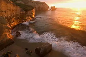 Waves Prints: Seascape view down the rugged coastline at Tunnel Beach with sea stacks and rock arches right at sunrise Tunnel Beach