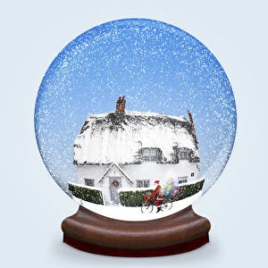 Snow globe of thatched cottage in winter snow