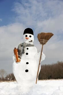 Snowman - with broom and bottle of Gin in snow landscape