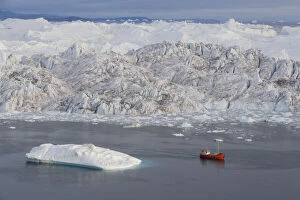 tourist boat in front of large icebergs