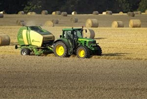 Tractor making bales of hay in freshly cut wheat field - September