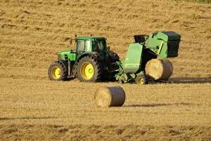 Farmland Collection: Tractor stopping to allow hay bale making machine to release bale of hay - September