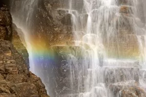 waterfall and rainbow - water cascading down a cliff with a rainbow forming in the waters spray