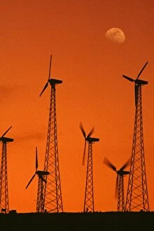 Wind turbines - at sunset, generating electricity at a windmill farm