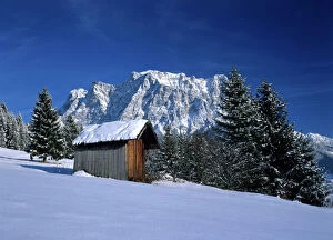 Winter scenery - hut and Zugspitze mountain in winter seen from the village of Erwald