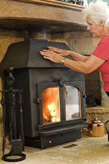 Woman - keeping warm warming hands on woodstove