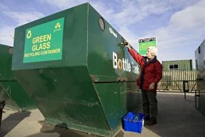 Bottles Gallery: Woman recycling glass bottle into large green skip