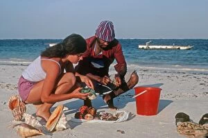 Woman tourist buying exotic shells from beach trader