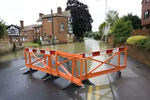 Roads Prints: Woman walking along flooded road into Tewkesbury near Abbey Gloucestershire UK