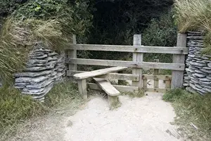 Track Prints: Wooden stile with dog gate between stone walls on cliff path North Devon UK