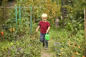 Young boy - in vegetable garden carrying watering can