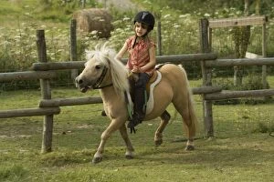Young girl riding Shetland Pony in paddock