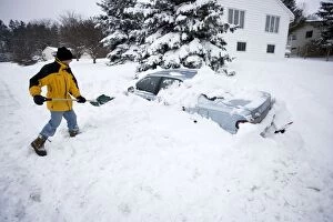 Images Dated 15th February 2007: Young man digging out car after snow storm, after
